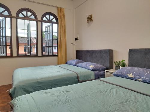 two beds in a room with windows at Grand Height Homestay 7A 10pax 4Rooms in Sibu