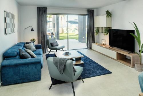 a living room with a blue couch and a tv at Villa Macaronesia in Adeje