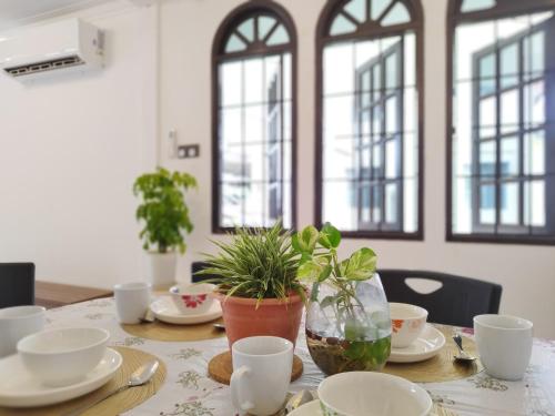 una mesa con platos y tazas y una planta en ella en Grand Height Homestay 7A 10pax 4Rooms, en Sibu