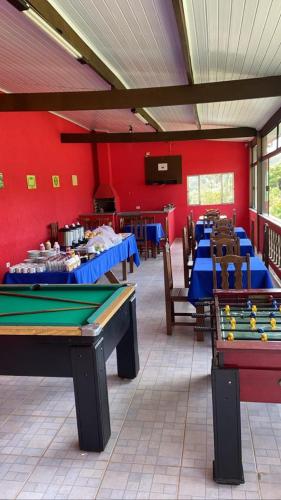 a room with ping pong tables in front of a red wall at Pousada Recanto dos Maximianos in Jarinu