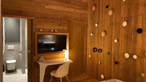 a room with a desk and a tv on a wooden wall at Chalet Jardin Alpin Valberg in Péone