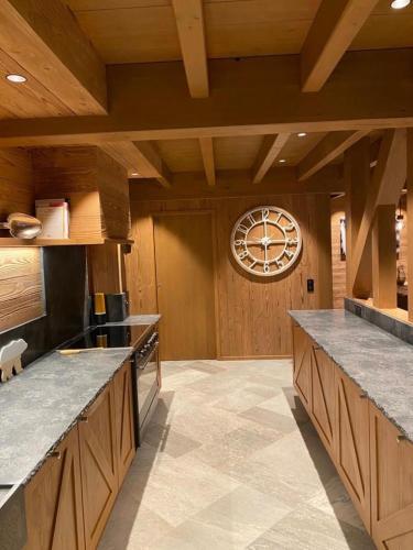 a kitchen with wooden cabinets and a clock on the wall at Chalet Jardin Alpin Valberg in Péone