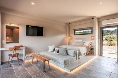 a bedroom with a bed and a couch and a tv at Alterra Vita Eco Villas in Neos Marmaras