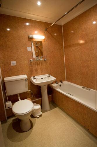 a bathroom with a toilet and a sink and a tub at Furzedown Hotel in Great Yarmouth
