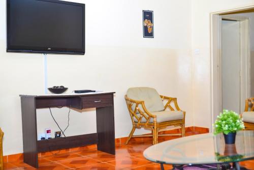 a living room with a desk and a chair and a television at Avon Garden Apartments Area 25 in Lilongwe