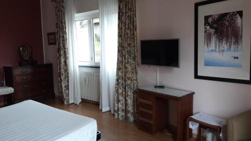 Schlafzimmer mit einem Bett, einem TV und einem Fenster in der Unterkunft Balcone Fiorito in Menaggio