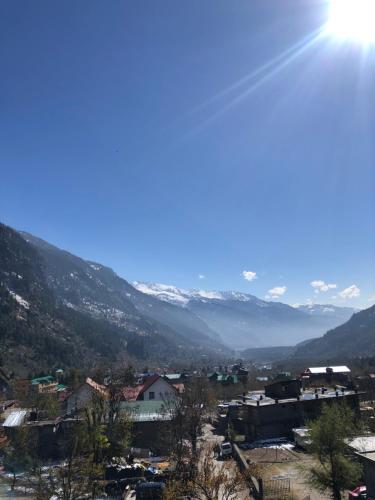 a view of a town with mountains in the background at Prāṇa Boutique Stays in Vashisht