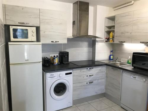 une cuisine avec un lave-linge et un micro-ondes dans l'établissement Appartement 2 Pièces Climatisé, Terrasse, Parking, Face au Lac Marin, à 900m de la Plage - Port Leucate - FR-1-81-66, à Port-Leucate