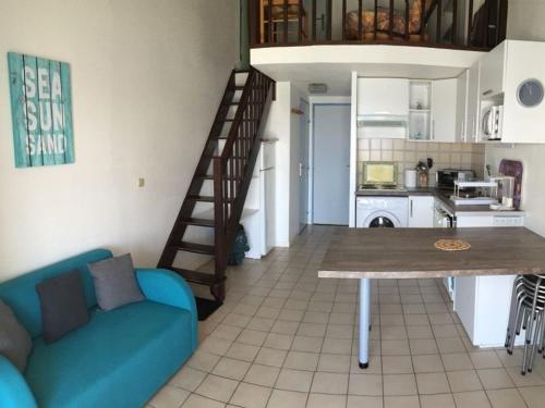 un salon avec un canapé bleu et une cuisine dans l'établissement Villa 3 pièces + mezzanine, 6 pers, Wifi, Parking privé, bord du lac, près de la plage - FR-1-81-80, à Port-Leucate