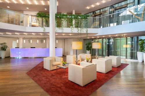 a lobby with white chairs and a red rug at INNSiDE by Meliá Dresden in Dresden
