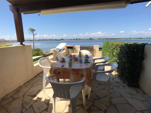 - une table et des chaises sur une terrasse avec vue sur l'eau dans l'établissement Villa Face au Lac avec Terrasse et Barbecue - 3 Pièces + Mezzanine pour 6 Personnes - FR-1-81-96, à Port-Leucate