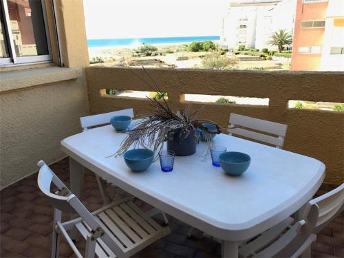 une table blanche avec 4 bols bleus sur un balcon dans l'établissement T2 à 50m de la plage, Parking privé, 4 pers - FR-1-81-117, à Port-Leucate