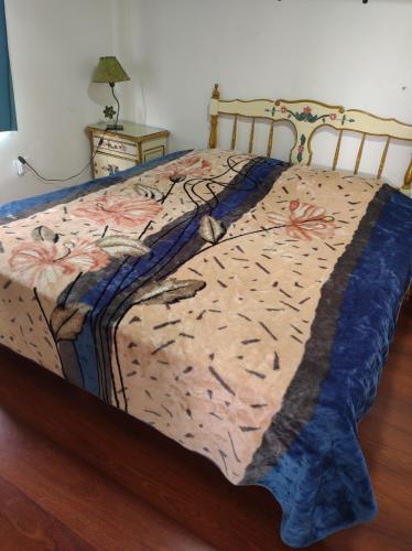 Una cama con edredón en un dormitorio en Departamentos Yexalen PA en El Calafate