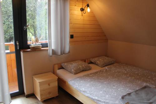 a small bedroom with a bed and a window at Gorczańskie Domki in Łopuszna