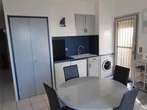 une cuisine avec une table, des chaises et un évier dans l'établissement Appartement T3, 6 Pers, Pieds dans l'Eau au Barcarès, Terrasse et Parking - FR-1-81-157, au Barcarès