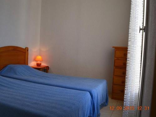 聖普里安海灘的住宿－Maison Saint-Cyprien, 3 pièces, 6 personnes - FR-1-225D-136，一间卧室配有一张带蓝色毯子的床和梳妆台