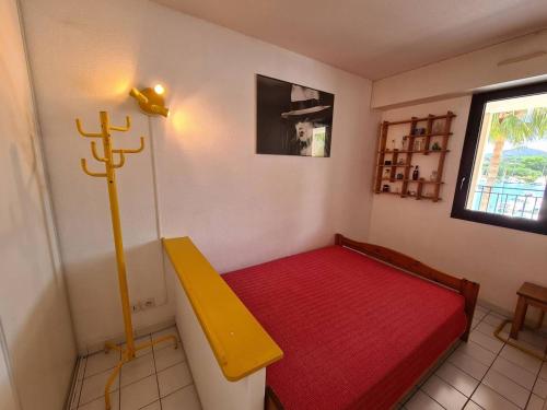 Cette petite chambre comprend un lit rouge et un banc jaune. dans l'établissement T2 Cabine, 4-6 pers, Parking, 150m plage - Argelès-sur-Mer - FR-1-388-16, à Argelès-sur-Mer