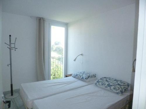 a bedroom with a bed with two pillows and a window at Appartement Banyuls-sur-Mer, 2 pièces, 4 personnes - FR-1-225C-21 in Banyuls-sur-Mer