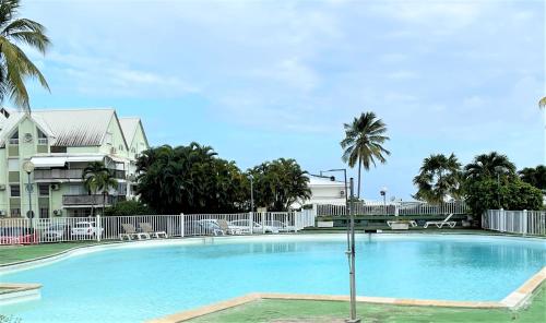 uma grande piscina com palmeiras e um edifício em Karukera By du fort em Le Gosier