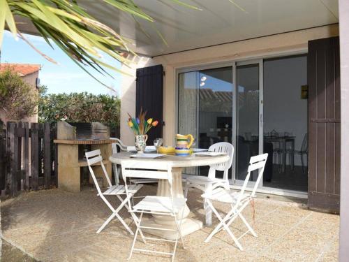 une table blanche et des chaises sur une terrasse dans l'établissement Maison avec jardin, piscine et parking - 4 couchages - plage à proximité - animaux acceptés - FR-1-225D-174, à Saint Cyprien Plage