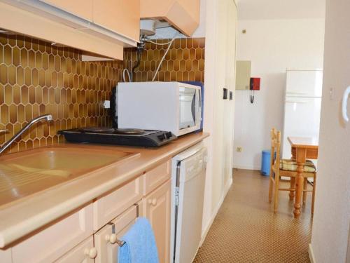une cuisine avec un évier et un micro-ondes sur un comptoir dans l'établissement Appartement familial climatisé, proche mer et commerces, 2 pièces, 4 couchages, terrasse équipée - FR-1-225-240, à Argelès-sur-Mer