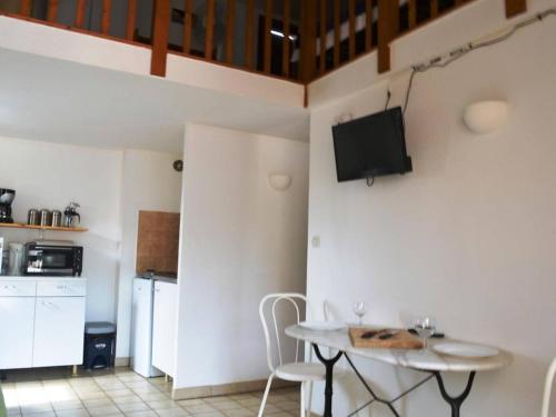 Il comprend une cuisine avec une table et une télévision murale. dans l'établissement Appartement familial 2 pièces + mezzanine, piscine, parking, à 1 km de la plage - Argelès-sur-Mer - FR-1-225-244, à Argelès-sur-Mer