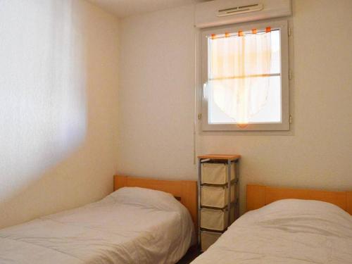 deux lits dans une chambre avec une fenêtre dans l'établissement Appartement 3 pièces avec terrasse, 6 couchages, piscine et parking privé à 300m de la plage à Narbonne Plage - FR-1-229B-125, à Narbonne