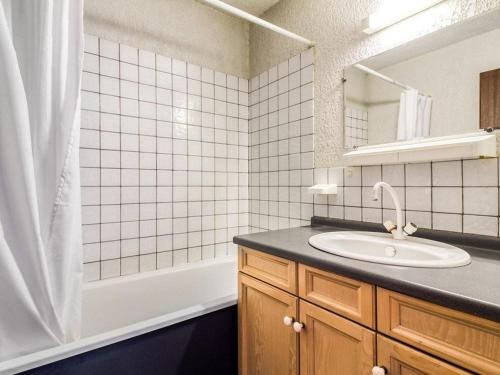 Un baño con lavabo, espejo y bañera. en Appartement T3 6 pers avec jardinet, BBQ, proche thermes, parking privé, 3 stations de ski à proximité - FR-1-402-9, en Esquièze - Sère
