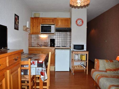 Elle comprend une petite cuisine équipée d'un réfrigérateur blanc et d'un canapé. dans l'établissement Studio ensoleillé 4 pers. avec balcon et parking, 200m des pistes, au cœur du Chinaillon - FR-1-241-107, au Grand-Bornand