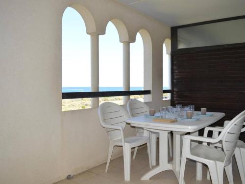 une table et des chaises blanches dans une chambre avec fenêtres dans l'établissement Appartement 3 pièces avec piscine et parking à Saint-Cyprien - FR-1-225D-315, à Saint-Cyprien