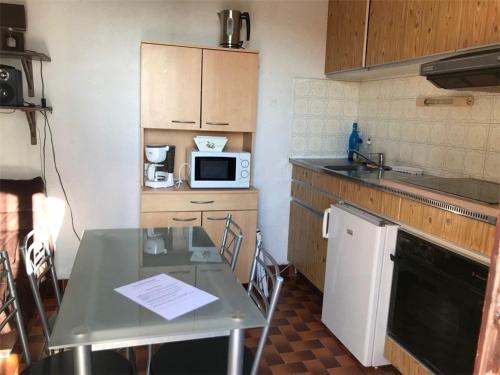 une petite cuisine avec une table et un micro-ondes dans l'établissement Villa 2 Pièces Climatisée avec Terrasse, Face à la Mer, Parking Privé, Proche Commerces et Plage - FR-1-81-343, à Port-Leucate