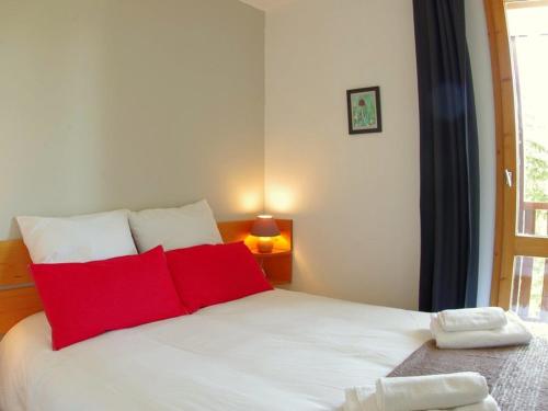 une chambre avec un lit blanc avec des oreillers rouges dans l'établissement Charmant 3 pièces à Valmorel avec balcons et casier à skis - FR-1-291-731, à Valmorel