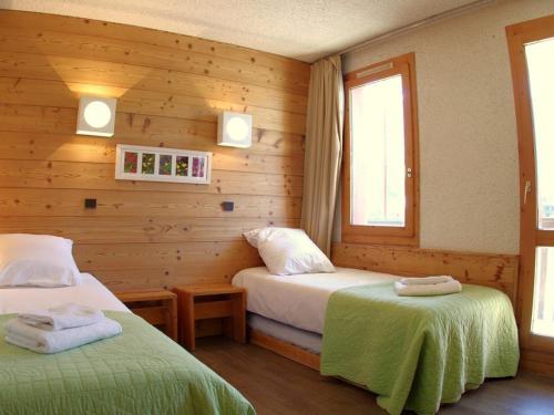 two beds in a room with wooden walls and a window at Appartement Valmorel, 1 pièce, 4 personnes - FR-1-291-748 in Valmorel