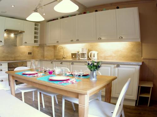 une cuisine avec une table en bois et des armoires blanches dans l'établissement Appartement cosy 3 pièces - 7 pers, skis aux pieds, 2 salles de bain, parking disponible - FR-1-291-747, à Valmorel