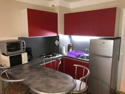 La cuisine est équipée de placards rouges, d'une table et d'un réfrigérateur. dans l'établissement Appartement T2 4 pers. face mer, parking privé à Port Barcarès - FR-1-81-336, à Port-Leucate