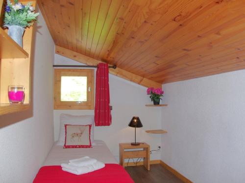 une chambre avec un lit rouge et un plafond en bois dans l'établissement Charmant 2 pièces pour 5 pers. à Valmorel, balcon sud, près ESF, animaux OK, ménage inclus - FR-1-291-756, à Valmorel