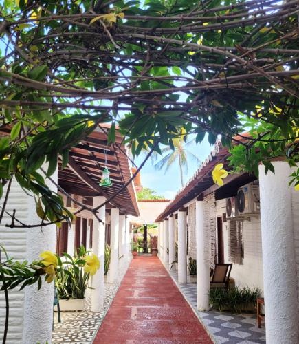 a walkway leading to a building with a roof at Pousada Roane - Taíba in Taíba