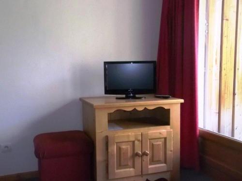 - une télévision installée au-dessus d'un support en bois à côté d'une fenêtre dans l'établissement T3 lumineux 7 pers, 100m des pistes, parking couvert, casier à skis, proche commerces et loisirs. - FR-1-262-115, à Les Estaris