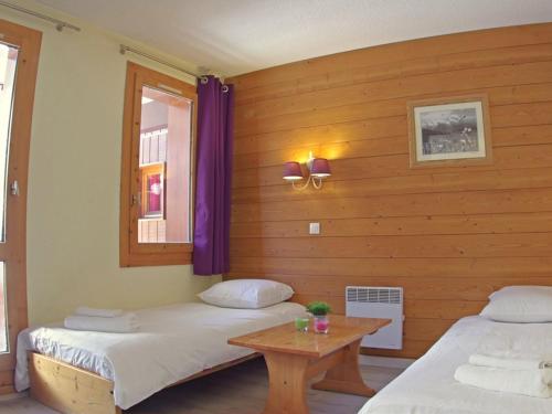 deux lits dans une chambre avec une table et des rideaux violets dans l'établissement Studio divisible rénové avec balcon et animaux acceptés à Valmorel - FR-1-291-788, à Valmorel