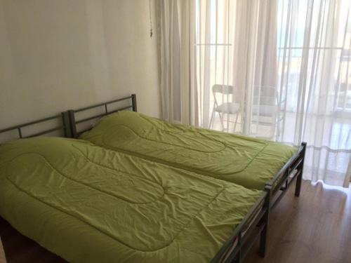 - un lit avec une couette verte dans une chambre dans l'établissement Appartement T3, 6 pers, BBQ, terrasse, parking, plage à prox. - FR-1-81-397, à Port-Leucate