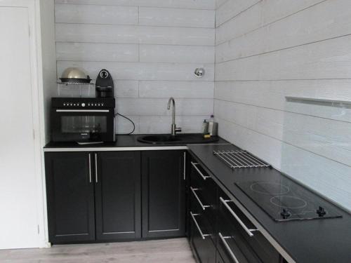 - une cuisine avec des placards noirs et un évier dans l'établissement Studio rénové 4 pers, centre-ville Cauterets, parking gratuit et navette - FR-1-234-146, à Cauterets