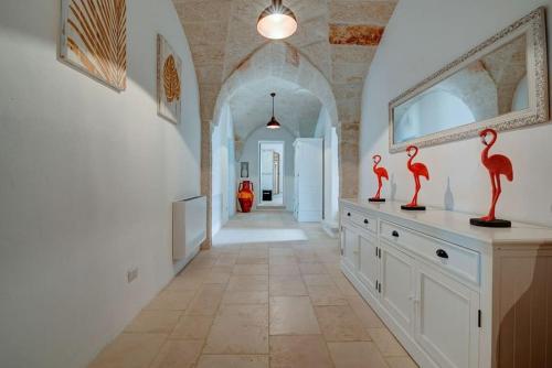 un pasillo con dos estatuas de flamencos rojos en un mostrador en Masseria Tufo Bianco by Raro Villas, en Fasano
