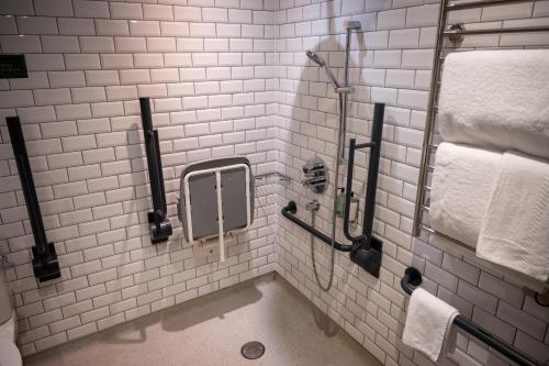 La salle de bains est pourvue de carrelage blanc, d'une douche et de serviettes. dans l'établissement Ely Hotel by Chef & Brewer Collection, à Camberley