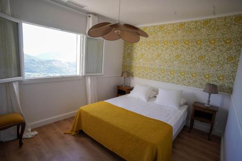 ein Schlafzimmer mit einem Bett mit einer gelben Decke und einem Fenster in der Unterkunft A CASA DI GEMMA in Appietto