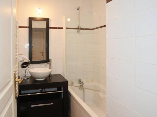 une salle de bain avec un lavabo, une baignoire et un miroir dans l'établissement Bel appartement avec piscine, sauna et hammam, 1 chambre, parking, animaux admis, wifi - FR-1-322-46, aux Orres