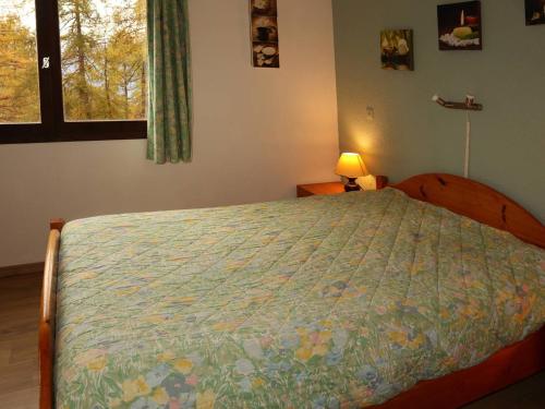 a bedroom with a bed with a comforter and a window at Appartement Les Orres, 2 pièces, 6 personnes - FR-1-322-83 in Les Orres