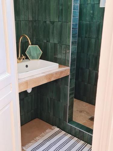 La salle de bains est pourvue d'un lavabo et d'un mur carrelé vert. dans l'établissement Appartement d'exception au cœur de Bordeaux, à Bordeaux