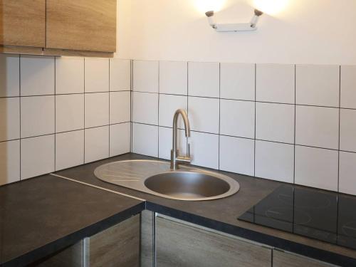 - un évier dans une cuisine aux murs carrelés blancs dans l'établissement Appartement 2 pièces, 6 pers, centre station - FR-1-322-29, aux Orres