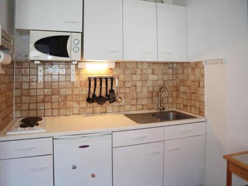 une cuisine avec des armoires blanches et un évier dans l'établissement Studio 4 pers. au cœur des Orres avec balcon et accès direct aux pistes - FR-1-322-181, aux Orres