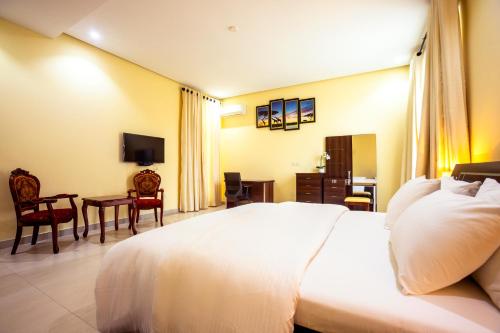 a bedroom with a large white bed and a desk at Rushmore - Luxury Suite in Lagos